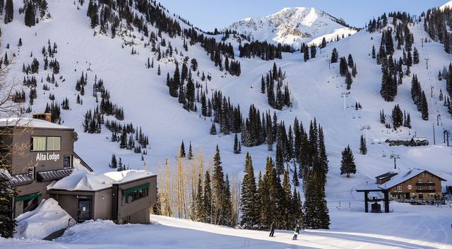 Alta Lodge at the foot of the snowy Alta slopes, with skiers passing the Wildcat base