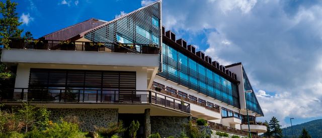 Hotel Bjelašnica, its long glass-fronted wings and timber balconies on the forested mountainside in summer