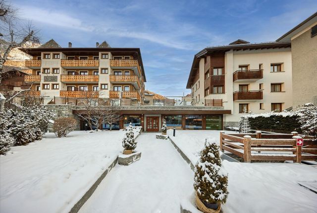 Hotel Rezia in Bormio with its timber balconies above a snowy garden path